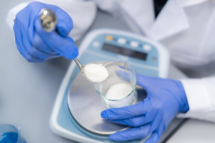 Shreegopal Polychem lab technician weighing a desiccant powder sample on a precision scale